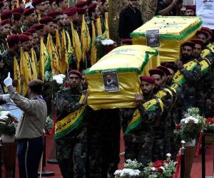 Combatientes de Hezbolá llevan los ataúdes de cuatro personas que murieron un día antes en explosiones de beepers, durante una procesión fúnebre en el suburbio sur de Beirut, Líbano.