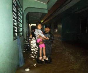 Un miembro de las Fuerzas Armadas carga a una niña en brazos luego de las inundaciones en el sector de Villa Neen, en La Ceiba, Atlántida.