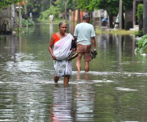 La gente vadea a lo largo de una calle inundada después de las lluvias monzónicas en Patsala, a unos 103 km de Guwahati, en el estado indio de Assam, el 23 de junio de 2023.