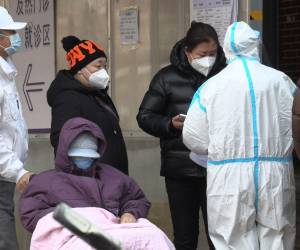 Esta captura de fotograma de un video de AFPTV muestra a una mujer hablando con un trabajador de la salud mientras la gente hace cola afuera de una clínica de fiebre en medio de la pandemia de covid-19 en Beijing el 14 de diciembre de 2022.