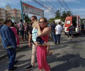 Imagen publicada por NSC Total que muestra a una mujer con un niño en brazos afuera de un preescolar privado donde un atacante mató a cuatro niños con un arma blanca, en Blumenau, estado de Santa Catarina, en el sur de Brasil, el 5 de abril de 2023.