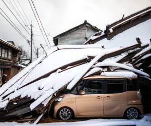 Un automóvil dañado yace debajo de un edificio derrumbado en la ciudad de Shika en el distrito de Hakui, prefectura de Ishikawa, el 8 de enero de 2024, después de que un gran terremoto de magnitud 7,5 sacudiera la región de Noto el día de Año Nuevo.