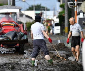 Residentes en la ciudad japonesa de Kurume limpian el barro en una carretera, tras las intensas lluvias.