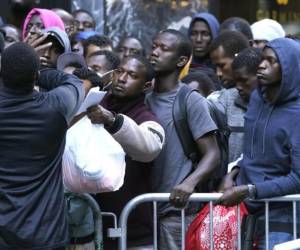 Centenas de migrantes esperan en fila frente a un centro de acogida ubicado en el Hotel Roosevelt en Manhattan en busca de un alojamiento gratuito