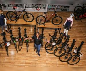 Gennie Flores posando y mostrando las 14 bicicletas que regalará Bike Mart en la Vuelta Ciclística de EL HERALDO.