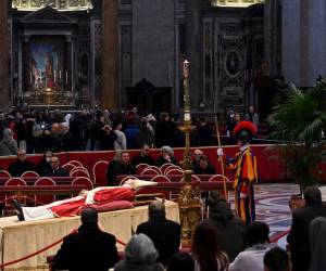 Los fieles entran en silencio por el pasillo central del templo católico más grande del mundo, la mayoría fotografiando con sus móviles el cuerpo del ex papa.