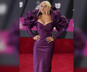 Christina Aguilera eligió un vestido morado para posar en la alfombra roja de los premios Grammy Latinos 2022. Con gran escote y volúmenes en los hombros, es un diseño de Zac Posen.