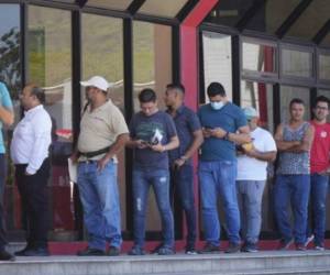 Imagen de archivo que muestra a varias personas haciendo fila frente a una agencia bancaria.