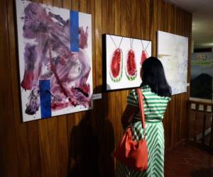 Una mujer aprecia las obras de la muestra. En la imagen, la pintura de Carmen Moncada, Haydeé Jiménez y Mei Lan Quan. Foto: Emilio Flores / El Heraldo.