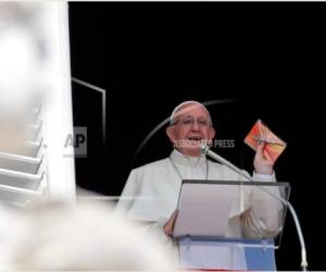 El papa Francisco muestra un crucifijo durante la oración del Angelus que hace desde la ventana de su estudio con vista a la plaza de San Pedro en el Vaticano, el domingo 16 de septiembre de 2018.