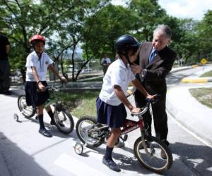 Jean Todt, presidente de la Federación Internacional de Automovilismo (FIA), ayuda a una niña a colocarse el casco durante el evento sobre seguridad vial en Honduras.