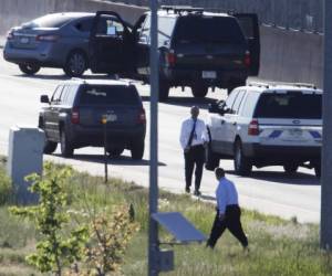 Detectives del Departamento de Policía de Denver, en primer plano, investigan el sitio donde un sedán Nissan, arriba a la izquierda, que era conducido por un chofer de Uber se estrelló contra un muro de retención junto a la carretera interestatal 25 al sur del centro de Denver, el viernes 1 de junio de 2018.