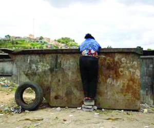 Una persona en situación de calle busca entre la basura alimento o cualquier objeto que pueda vender para ganar unos pocos lempiras.