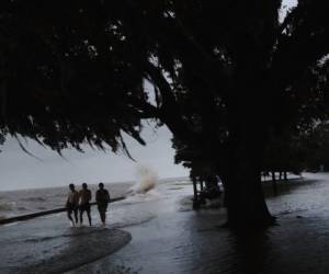 MANDEVILLE, LOUISIANA - JULY 13: People walk through floodwater along the shore of Lake Pontchartrain after it topped the flood wall in the wake of Hurricane Barry on July 13, 2019 in Mandeville, Louisiana. The storm, which made landfall this morning as a category one hurricane near Morgan City, caused far less damage and flooding than had been predicted. Flash flood watches were issued throughout much of Louisiana and as far east as the Florida panhandle as the storm was expected to dump more than a foot of rain in many areas and up to 25 inches in some isolated locations. Many areas are now expected to get less than half of the original projections. Scott Olson/Getty Images/AFP== FOR NEWSPAPERS, INTERNET, TELCOS & TELEVISION USE ONLY ==