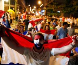 Un joven tiene una bandera nacional nacional de Paraguay mientras marcha con otros en protesta contra el proyecto de cambiar la constitución del país, en Asunción, Paraguay.