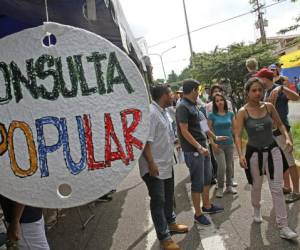 Al grito de 'viva Venezuela', miles de personas _algunas portando banderas venezolanas y gorras tricolores_ se aglomeraron al amanecer en iglesias, centros deportivos, plazas y calles de la capital, que fueron habilitadas como centros electorales.