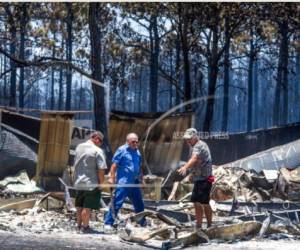 En esta fotografía de archivo del 25 de junio de 2018, residentes rescatan sus pertenencias de sus casas quemadas en Eastpoint, Florida.