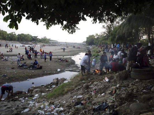 Entre basura y secando ropa en piedras, migrantes siguen varados en río Suchiate