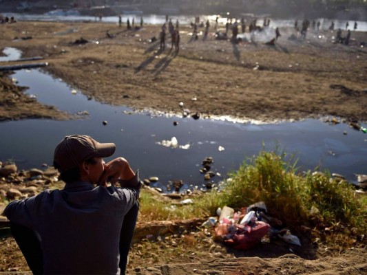 Entre basura y secando ropa en piedras, migrantes siguen varados en río Suchiate