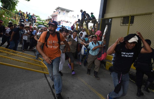 FOTOS: Así fue el momento en el que la caravana migrante de hondureños rompió los portones e ingresó a México