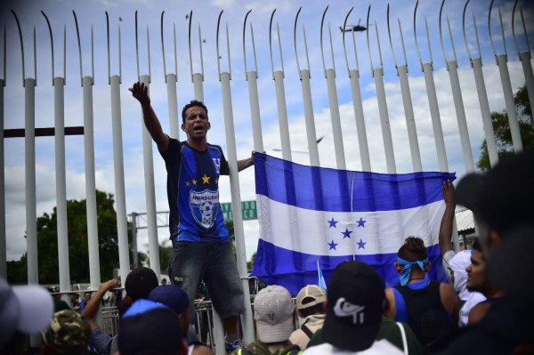 FOTOS: Así fue el momento en el que la caravana migrante de hondureños rompió los portones e ingresó a México