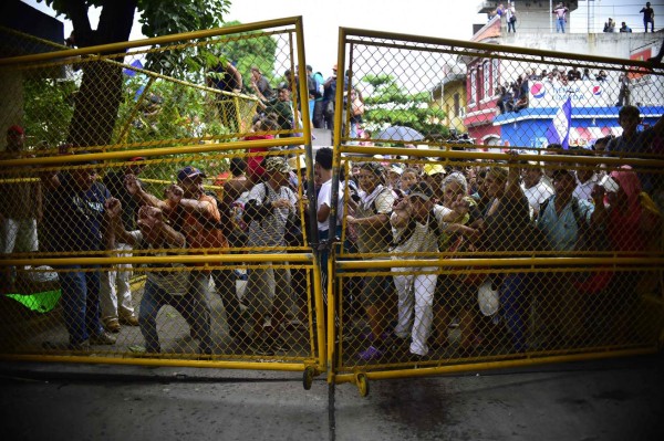 FOTOS: Así fue el momento en el que la caravana migrante de hondureños rompió los portones e ingresó a México