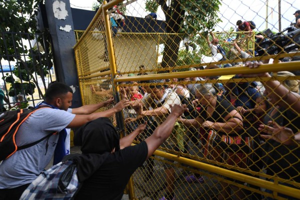 FOTOS: Así fue el momento en el que la caravana migrante de hondureños rompió los portones e ingresó a México