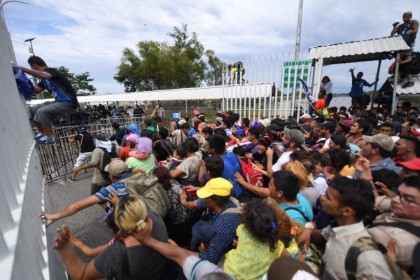 FOTOS: Así fue el momento en el que la caravana migrante de hondureños rompió los portones e ingresó a México