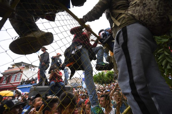 FOTOS: Así fue el momento en el que la caravana migrante de hondureños rompió los portones e ingresó a México