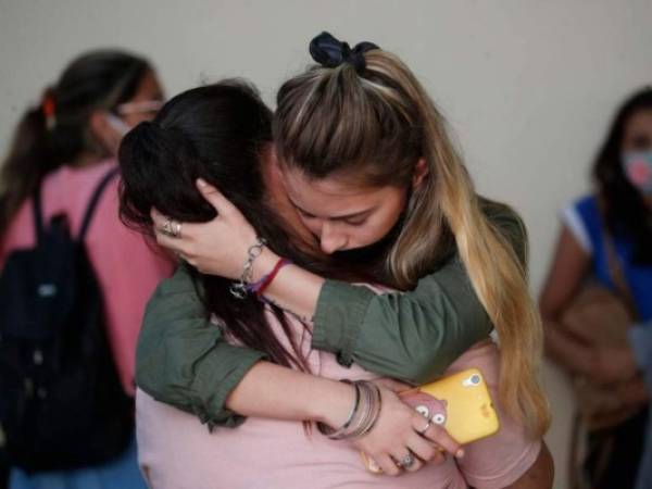 Amigas de Úrsula Bahillo, de 18 años y que fue encontrada en un campo apuñalada hasta la muerte el lunes, se abrazan durante su velorio en Rojas, Argentina. Foto: AP