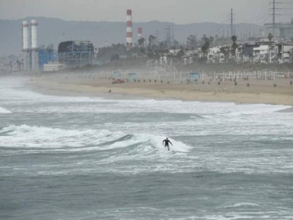 Un surfista atrapa una ola en Manhattan Beach, California, el 15 de enero de 2022. El Servicio Meteorológico Nacional de EE. UU. emitió avisos de tsunami para toda la costa oeste de los Estados Unidos luego de una erupción volcánica masiva en el Océano Pacífico en Tonga. Foto: AFP