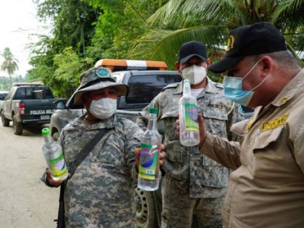 Bomberos y policías municipales revisan envases del aguardiente Dominó.