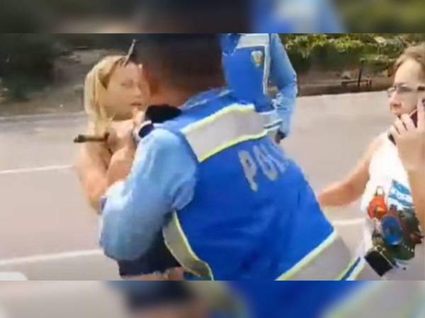 Momento en que el agente empuja con fuerza a la mujer por varios metros.