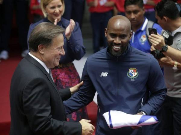 El jugador del equipo nacional de fútbol de Panamá, Felipe Baloy (R), recibe del presidente panameño Juan Carlos Varela la bandera nacional panameña, antes de su participación en la Copa Mundial de la FIFA, durante una ceremonia en el Palacio presidencial Las Garzas en la ciudad de Panamá.