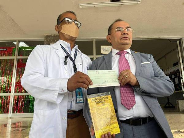 Así fue el momento en que la autoridad del Hospital Escuela recibía de manos del galeno el cheque. Dennis Chirinos acudió a entregarlo portando también la Constitución de la República.