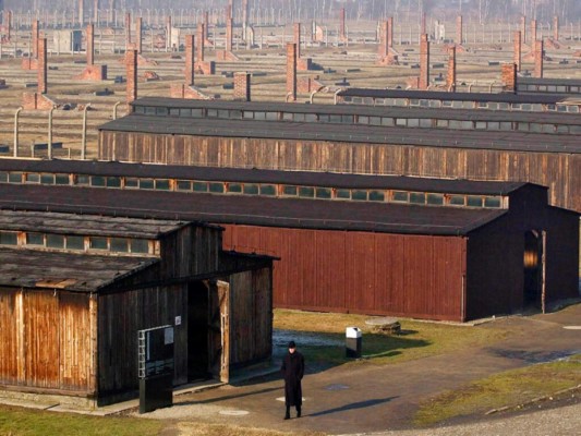 Fotografía de archivo del 17 de enero de 2005 de un visitante caminando junto a los barracones de madera del antiguo campo de exterminio nazi de Auschwitz-Birkenau en Oswiecim, Polonia. (AP Foto/Czarek Sokolowski, Archivo).