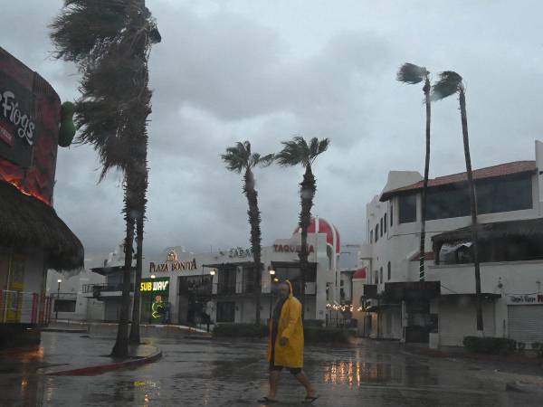 Un hombre camina por una calle en Cabo San Lucas, estado de Baja California, México, mientras la lluvia y las ráfagas de viento del huracán Hilary llegan a la zona, el 19 de agosto de 2023.