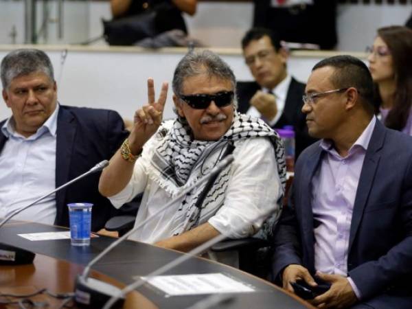 El ex rebelde de las FARC, el legislador Jesús Santrich, hace la se al de la victoria a periodistas durante una sesión de la cámara baja en Bogotá, el miércoles 12 de junio de 2019.