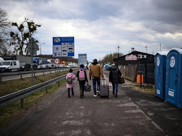 Las refugiadas ucranianas Julia (2.a izquierda), de 32 años, y Miroslava (izquierda), de 11, se alejan con familiares (derecha) que las recogieron después de cruzar la frontera entre Ucrania y Polonia al salir de Ucrania en el cruce fronterizo de Dorohusk, al este de Polonia. el 6 de abril de 2022.