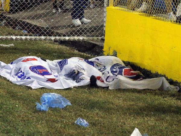 Los cuerpos de las víctimas se ven cubiertos con banderas de Alianza luego de una estampida durante un partido de fútbol entre Alianza y FAS en el estadio Cuscatlán en San Salvador, El Salvador.