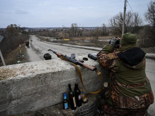 Un militar ucraniano mira a través de binoculares hacia la ciudad de Stoyanka en un puesto de control antes del último puente en la carretera que conecta Stoyanka con Kiev, el 6 de marzo de 2022.