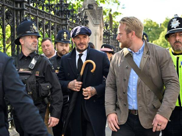 David Beckham, de 47 años, fue descubierto por la prensa mientras esperaba en la fila, vestido con traje, corbata y abrigo negros. Llevaba también una gorra y un paraguas del mismo color.