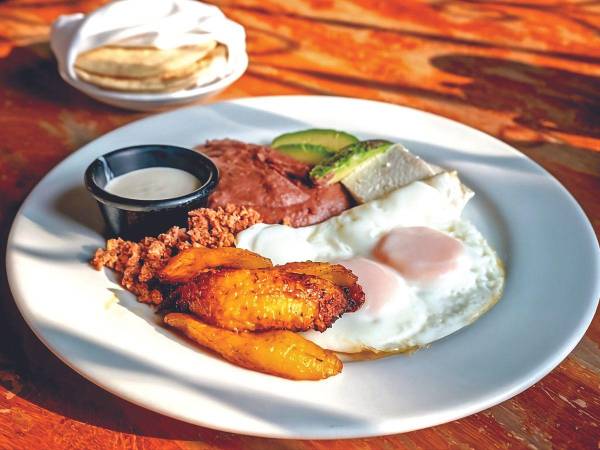 El desayuno típico incluye una combinación de alimentos como huevos, plátanos fritos, frijoles refritos, queso, aguacate y tortillas. Es un platillo completo y variado.