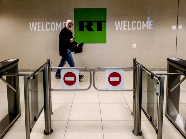 Esta foto de archivo tomada el 8 de junio de 2018 muestra a un hombre mientras pasa frente a un puesto de control de la compañía de televisión Russia Today (RT) en Moscú.