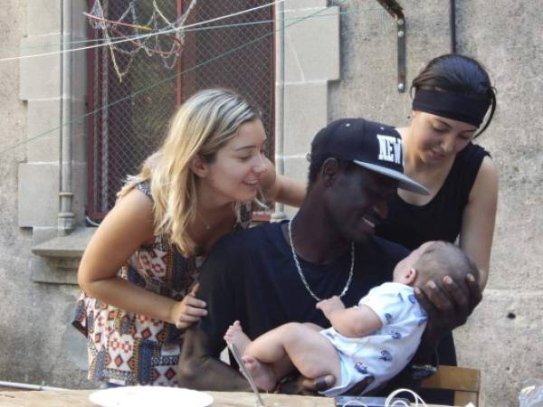 En el cruce de mundos que es la península ibérica, un joven de Senegal sujeta a un bebé español ante la mirada de una muchacha marroquí -vestida de negro- y la trabajadora social que los atiende en el castillo que sirve como casa de acogida.