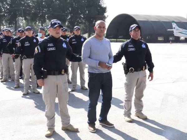 Esta fotografía distribuida por la policía de Colombia muestra al colombiano Álvaro Córdoba (C), hermano de la senadora Piedad Córdoba, caminando escoltado por agentes de la Interpol antes de ser extraditado a Estados Unidos en el Aeropuerto Internacional El Dorado de Bogotá el 19 de enero de 2023.