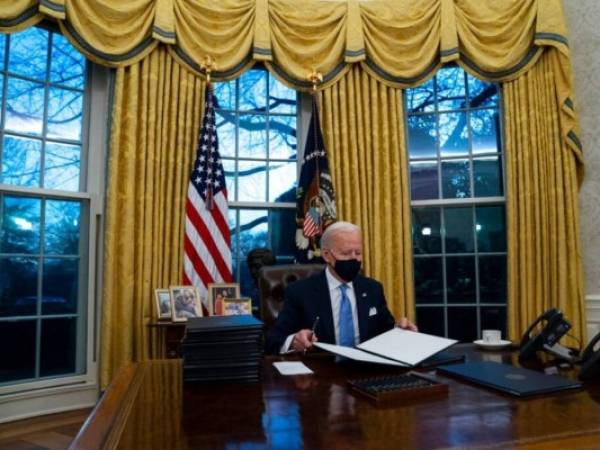 El presidente de Estados Unidos, Joe Biden, firma una serie de órdenes ejecutivas en la Oficina Oval de la Casa Blanca, el 20 de enero de 2021, en Washington. Foto: AFP