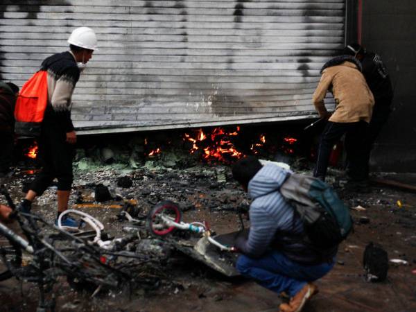 Trabajadores de supermercados inspeccionan los daños causados por el fuego después de que estallaron enfrentamientos entre la policía antidisturbios y manifestantes antigubernamentales en Puno, Perú, el 9 de enero de 2023.