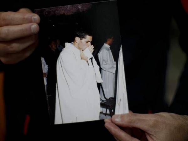 Andrés Gioeni muestra una fotografía de su ceremonia de ordenación para convertirse en sacerdote en 2000, luego de regresar a casa del obispado donde inició el proceso de apostasía en Buenos Aires, Argentina. Foto: AP