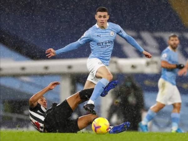 Phil Foden, centro, del Manchester City, evade la barrida de Isaac Hayden, del Newcastle, en partido por la Liga Premier en el Estadio Etihad de Manchester, Inglaterra, el sábado 26 de diciembre de 2020. (Jason Cairnduff/ Pool vía AP)